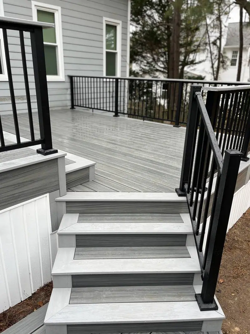 Grey composite deck stairs with black aluminium railing and white risers