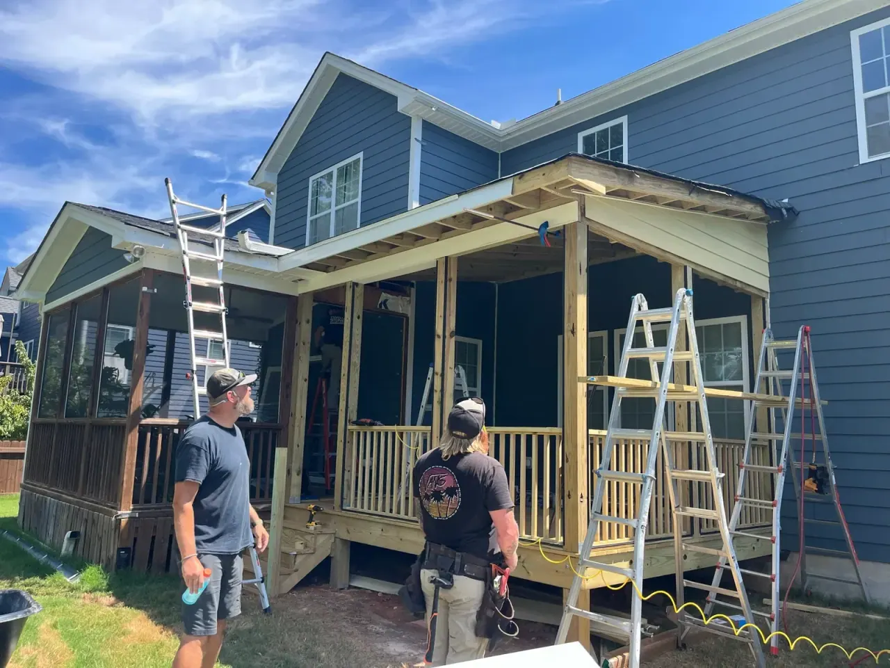 Mission Decks crew working on a screened porch build on a blue-sided home
