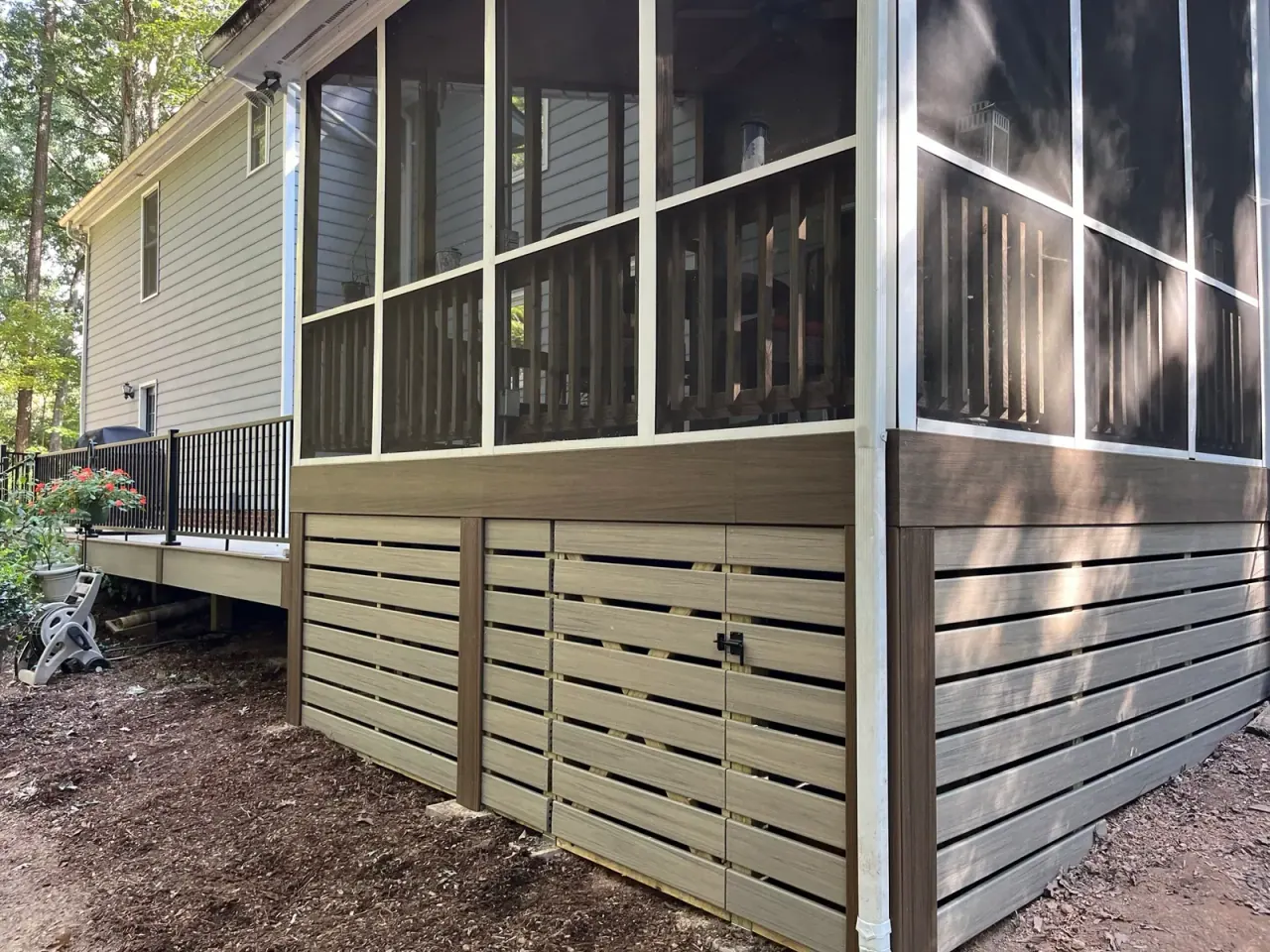 Corner view of a screened porch with horizontal skirting and dark screen frames