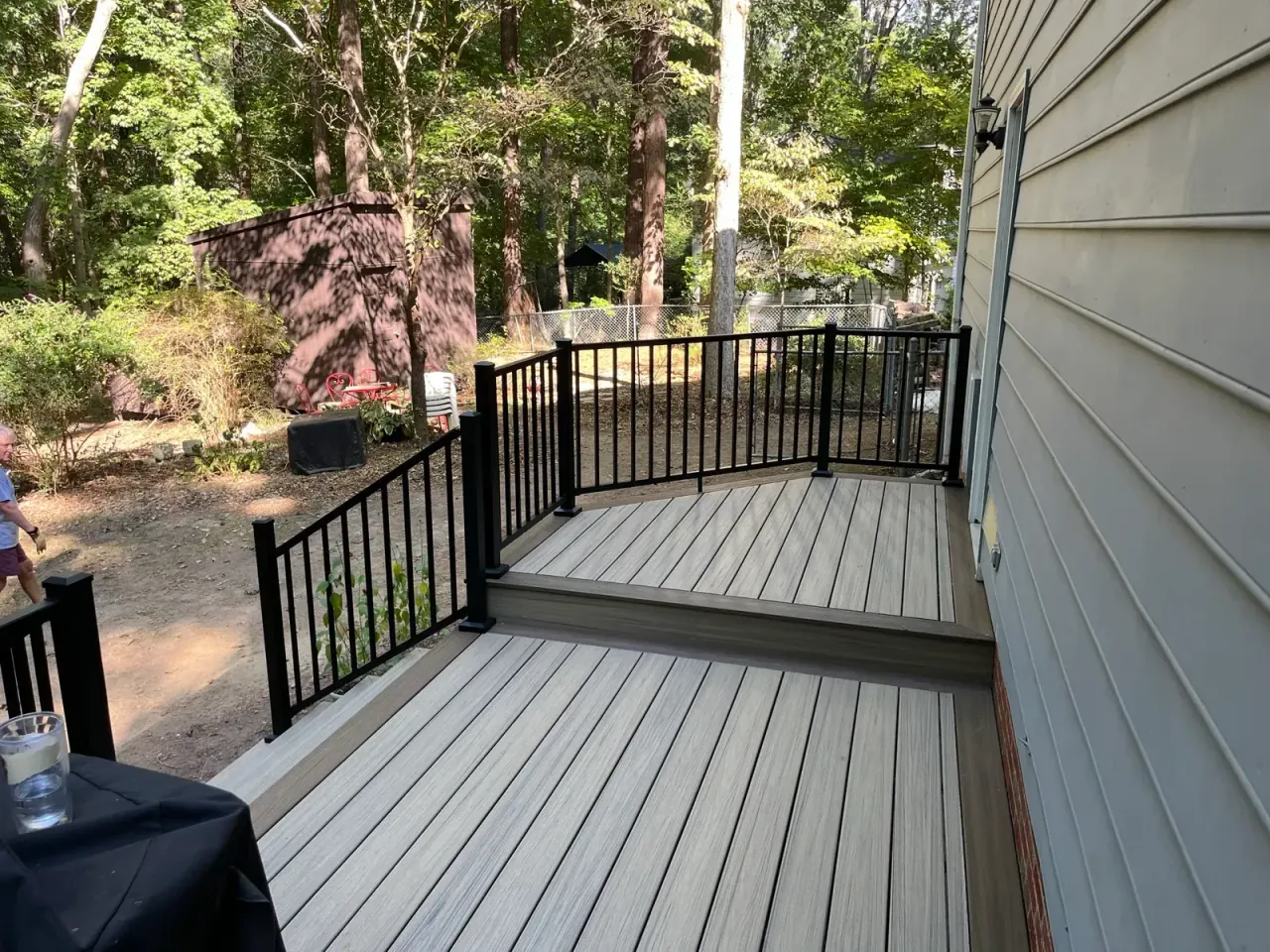 Composite deck with black aluminum railing at the edge of a wooded lot