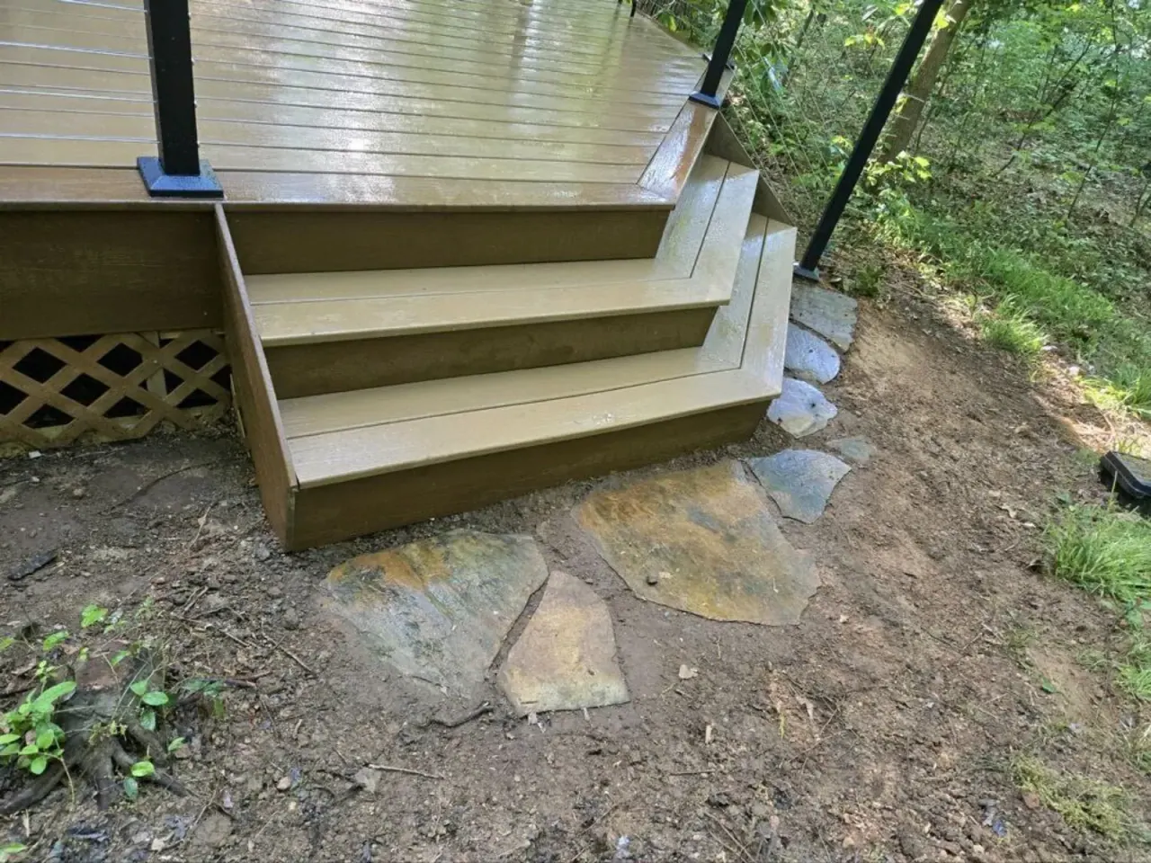 Deck stairs descending to a natural stone landing with lattice skirting