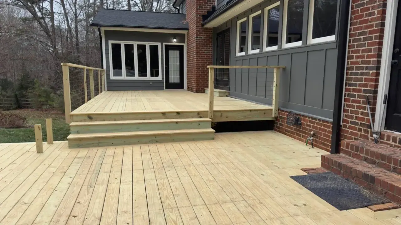 New pressure-treated deck platform against a dark gray and brick home