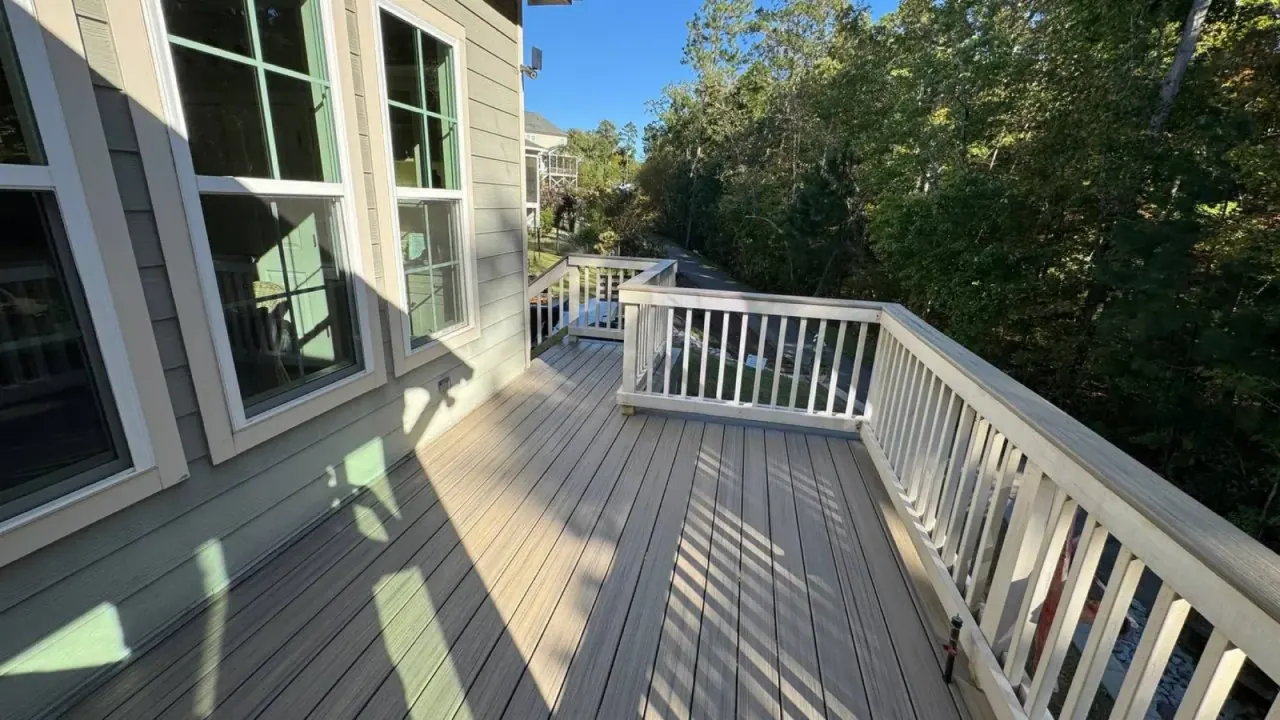 Sunlit composite deck with white railing and wooded backdrop