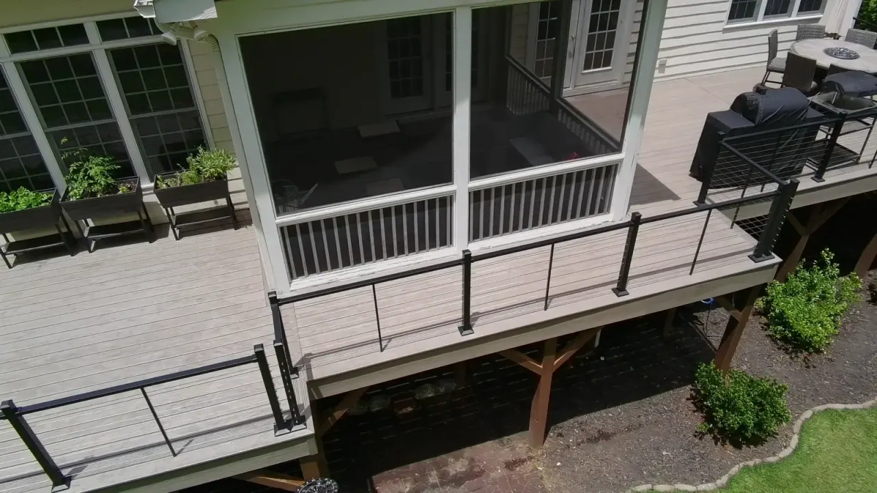 Aerial view of a composite deck and screened porch with black railing and grill station