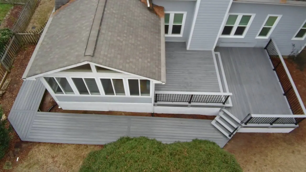 Aerial view of a grey composite deck wrapping a screened porch on a cream-sided home